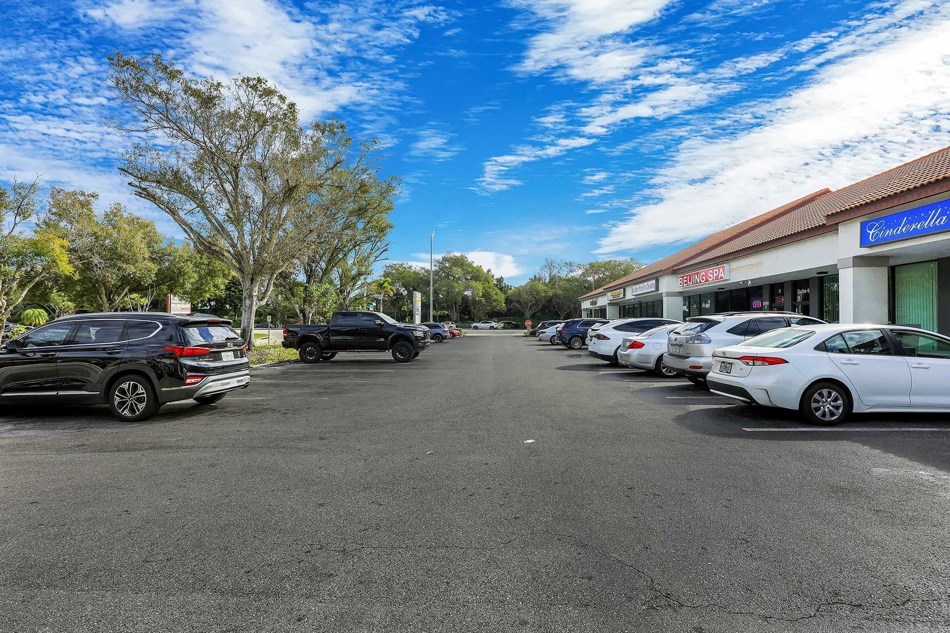 Parking lot with cars in front of a strip mall on a sunny day.
