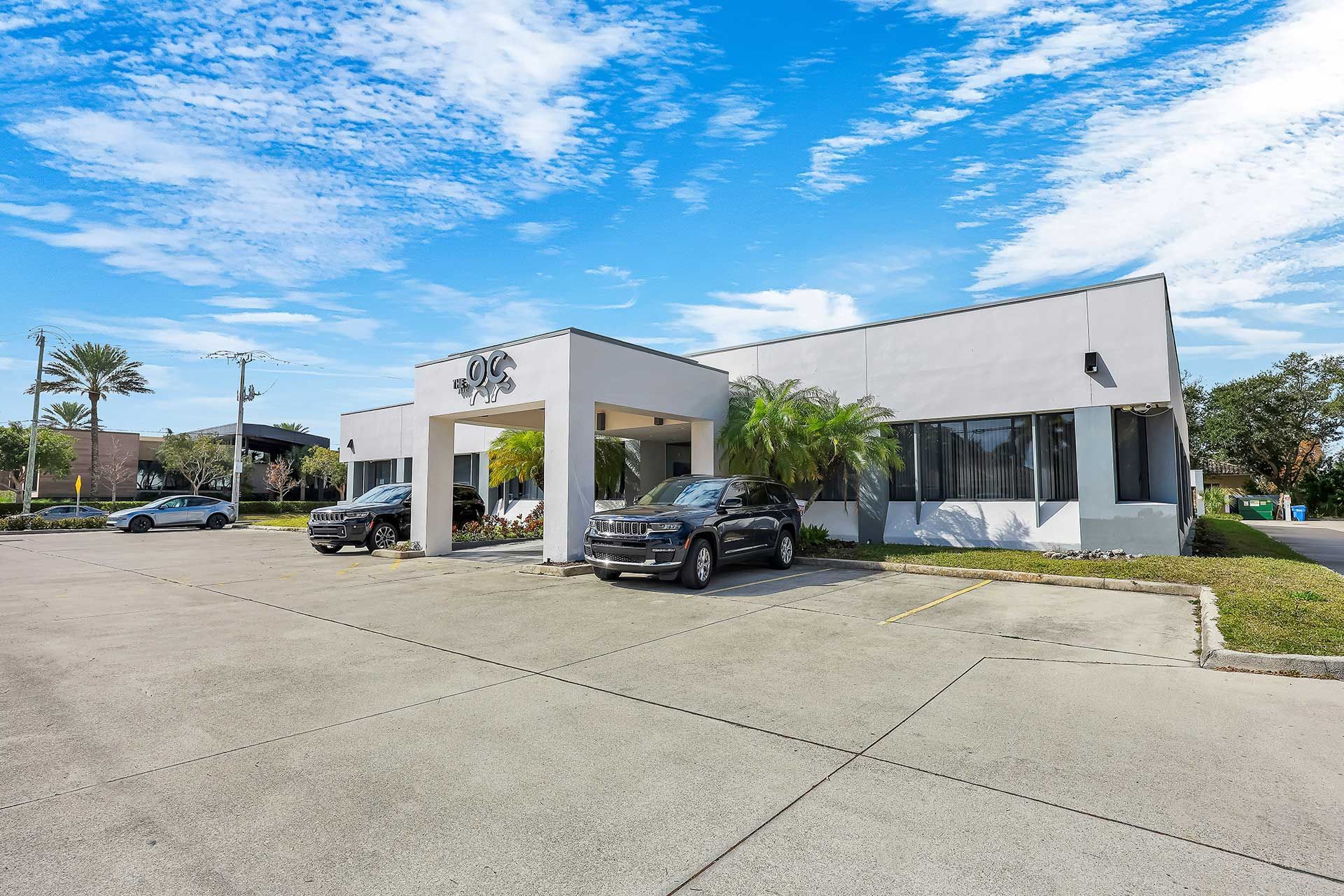 White building with parked cars under a bright blue sky.