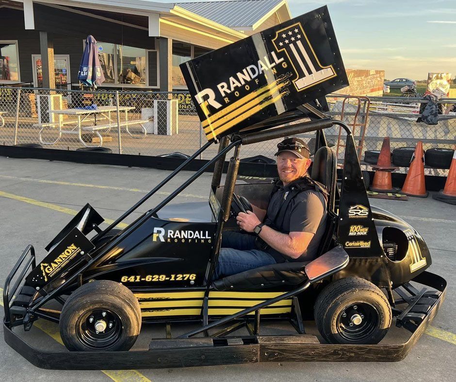 A person sits in a black and yellow sprint kart with