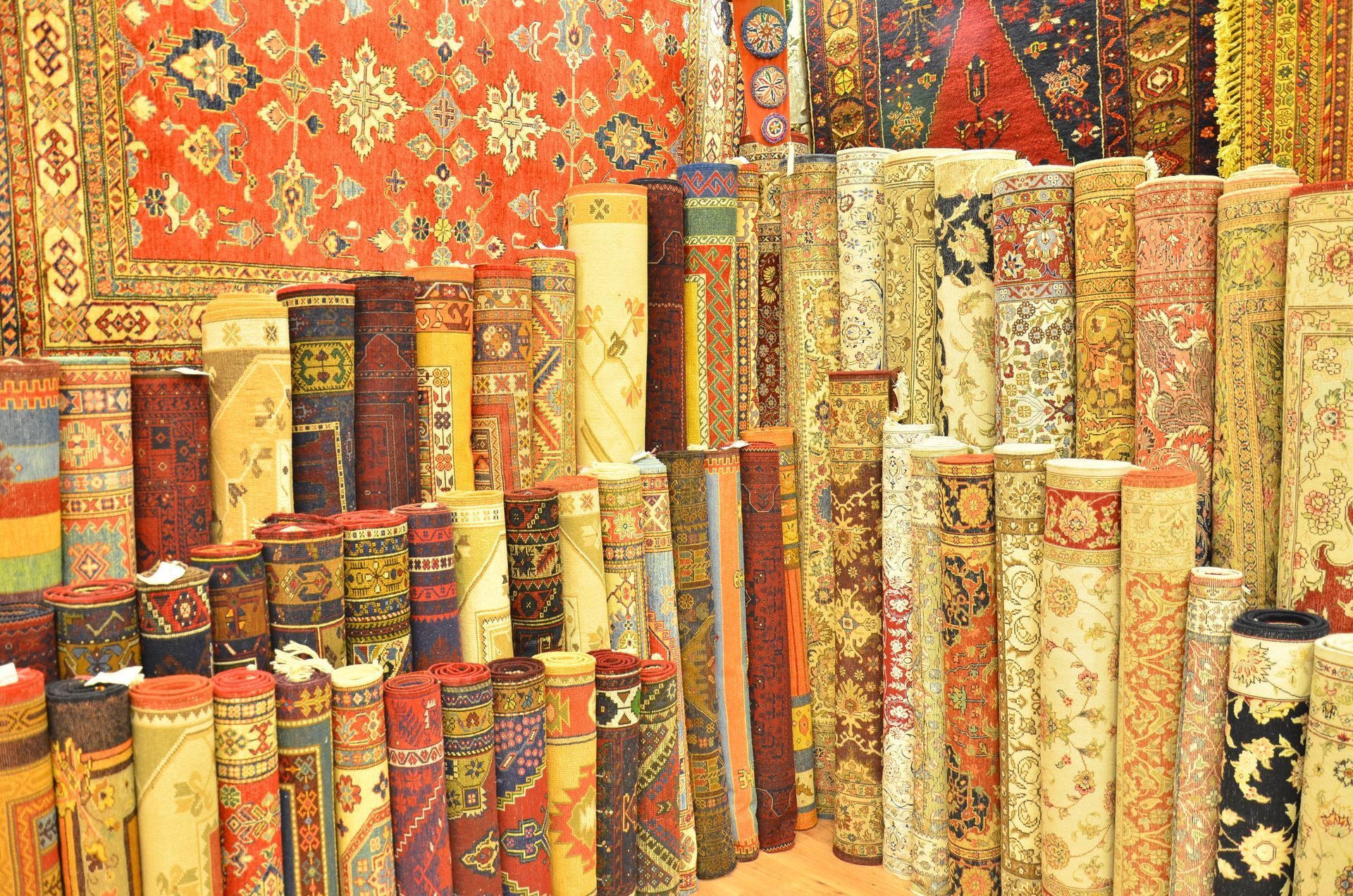 Rolled carpets in various colors and patterns displayed in a shop.