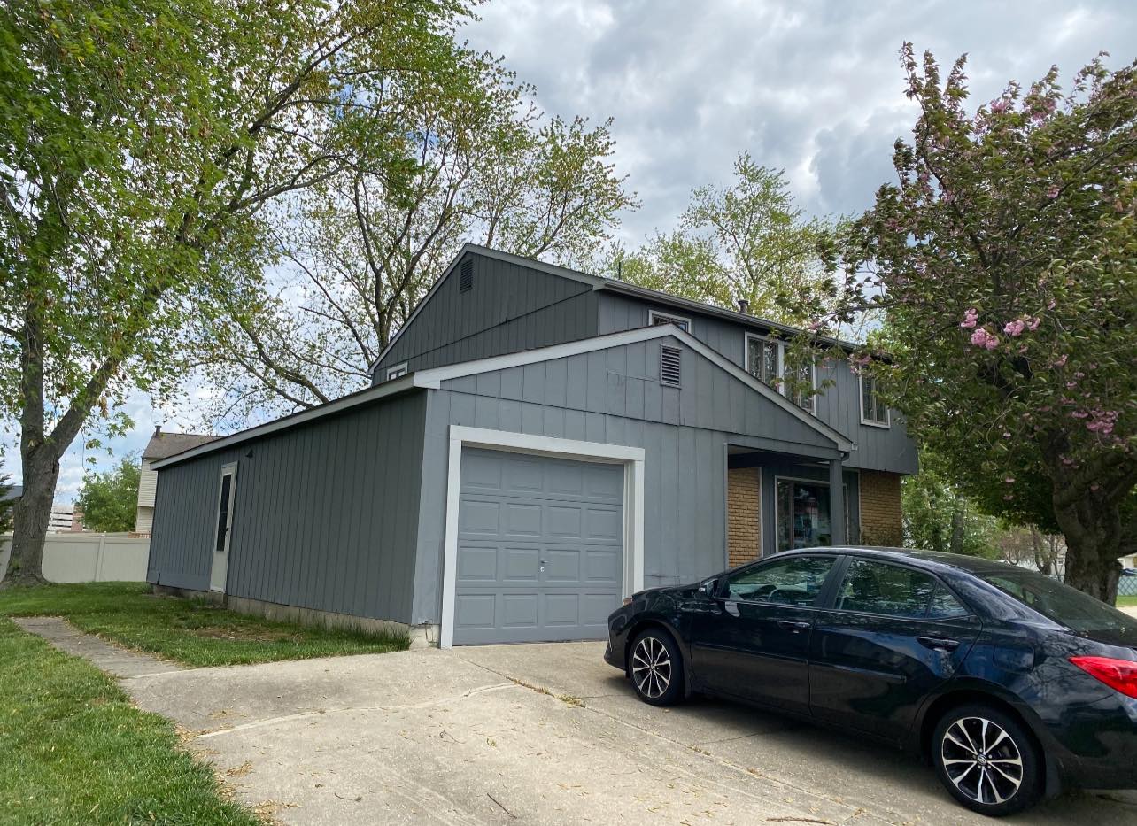 Gray house siding with a parked black car