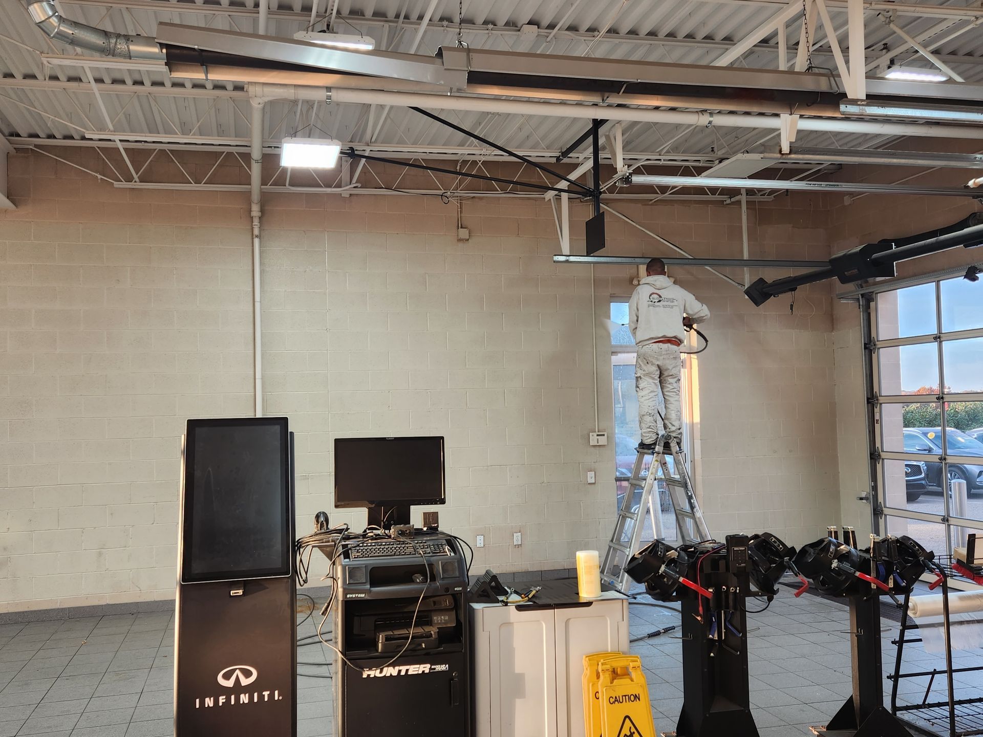 A man is standing on a ladder in a room with a sign that says infiniti on it.