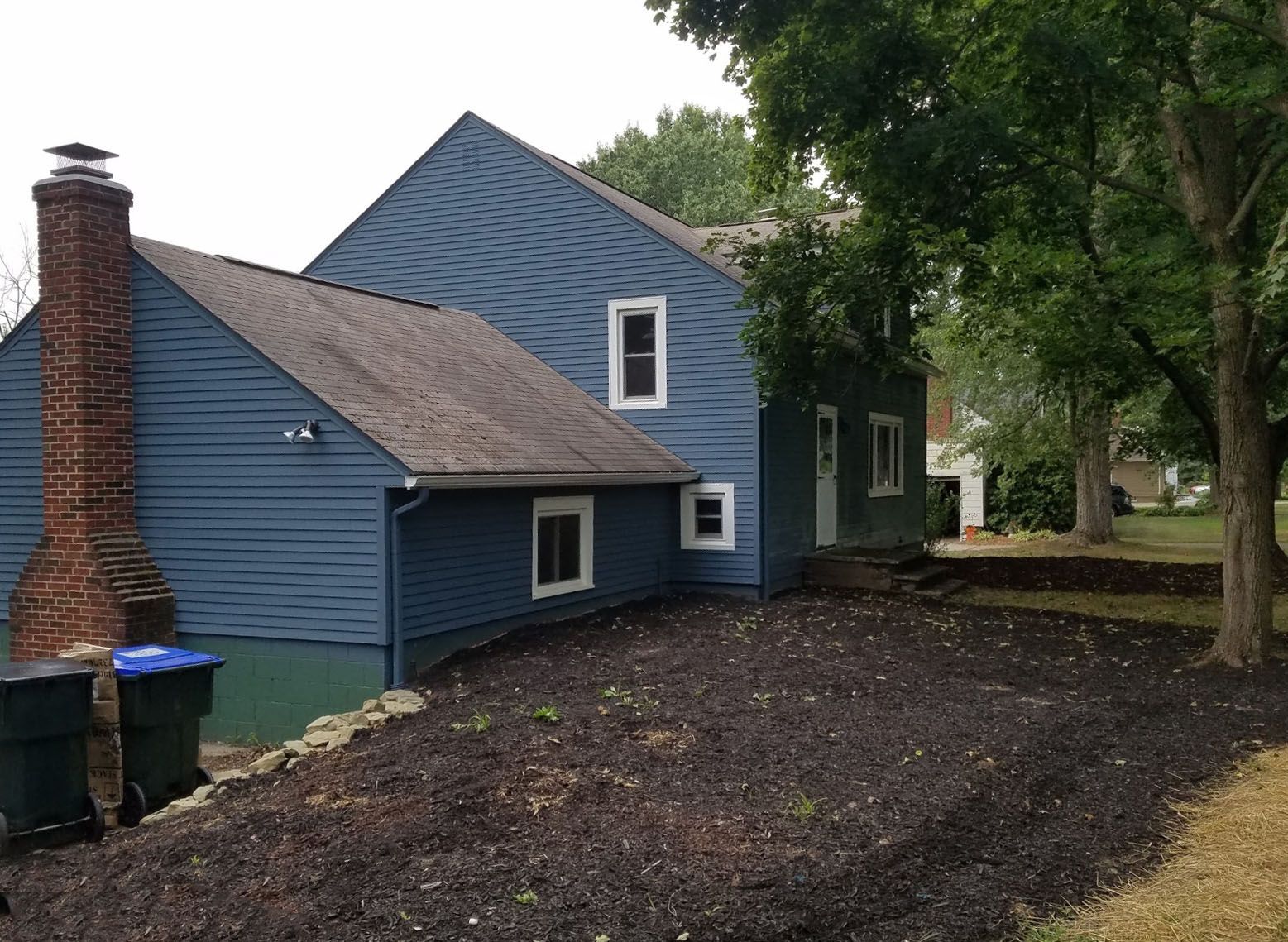 The back of a blue house with a brick chimney