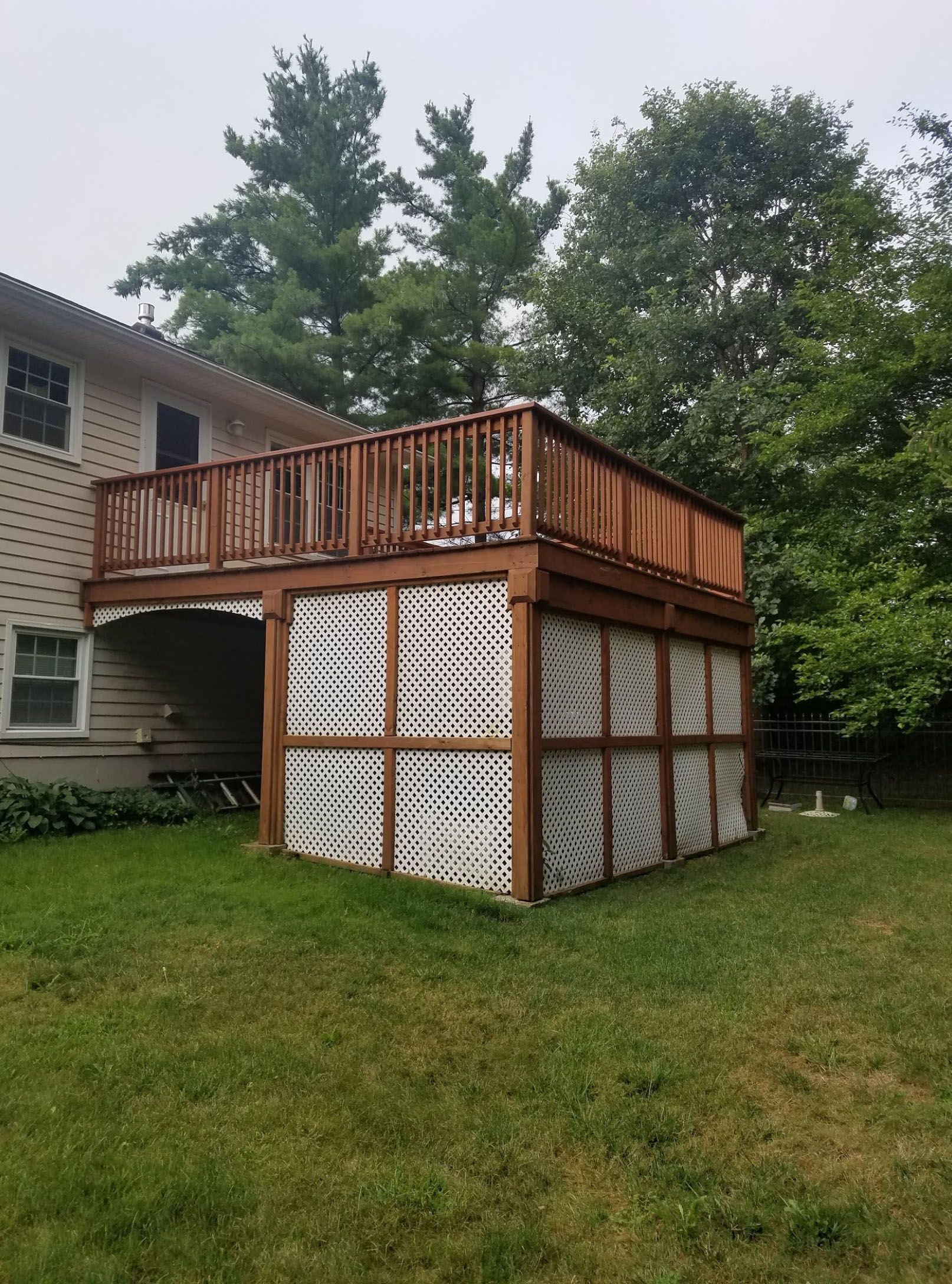 A wooden deck with a screened in area underneath it