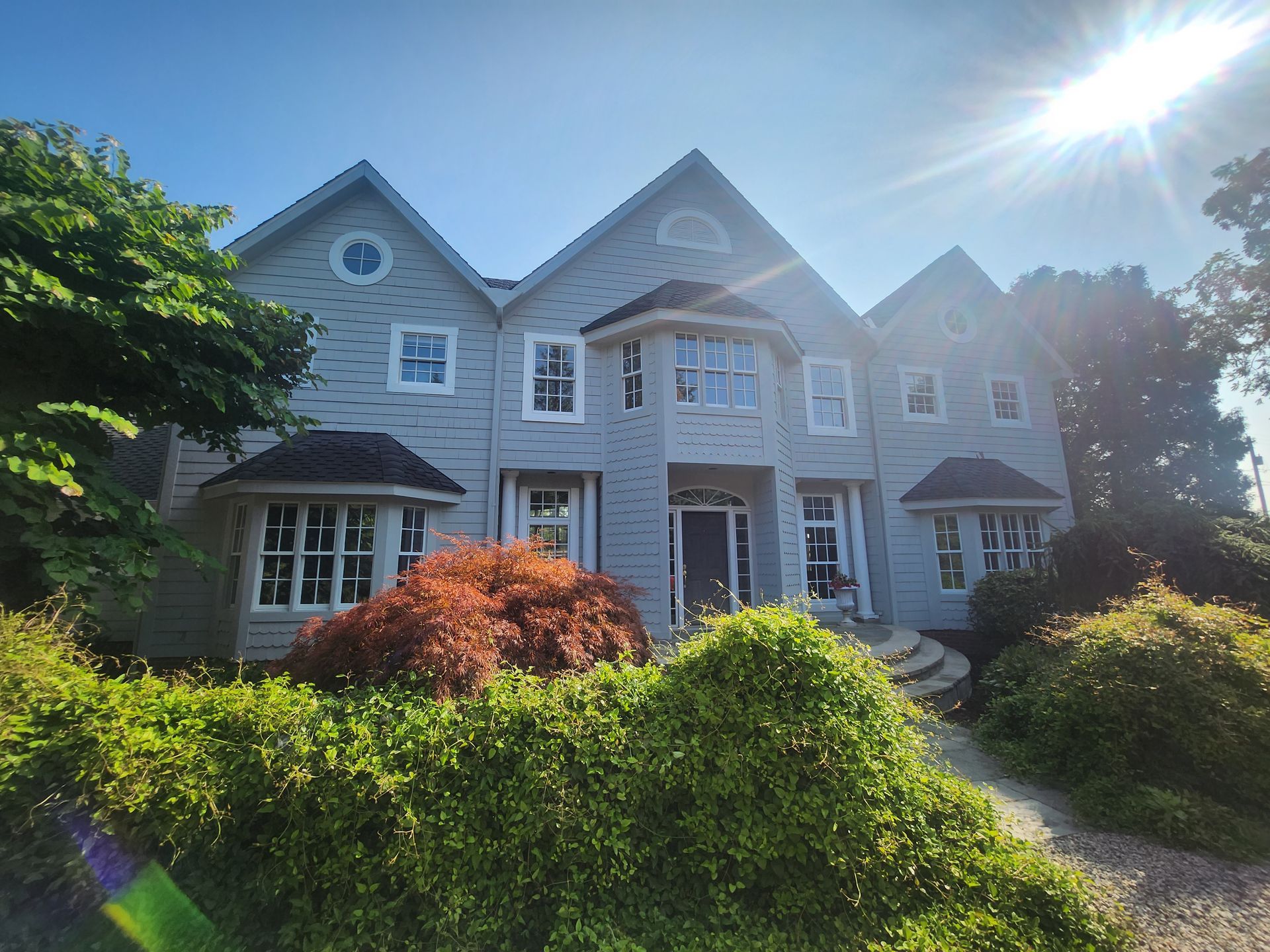 A large white house is surrounded by trees and bushes