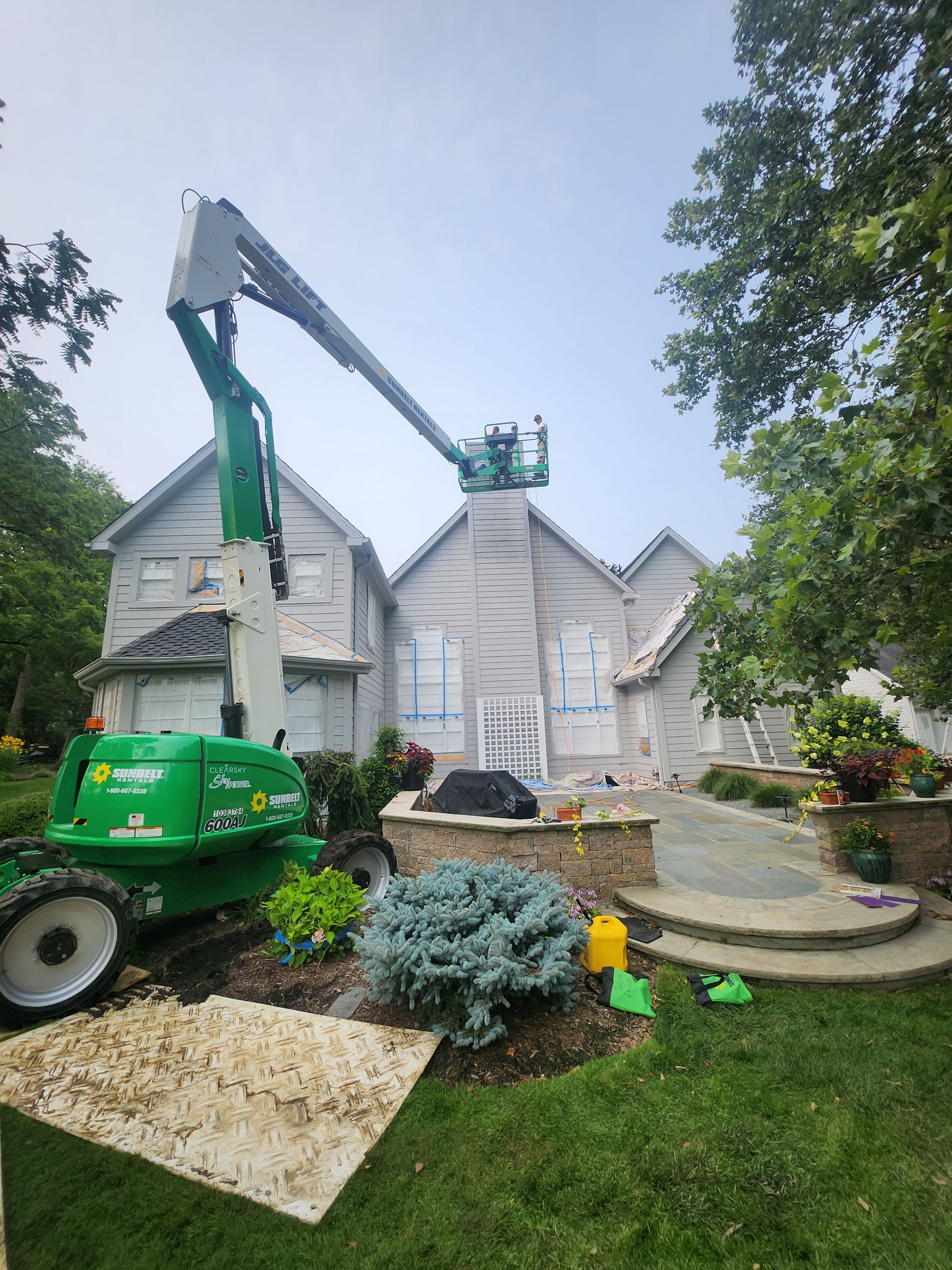 A green crane is sitting in front of a house.