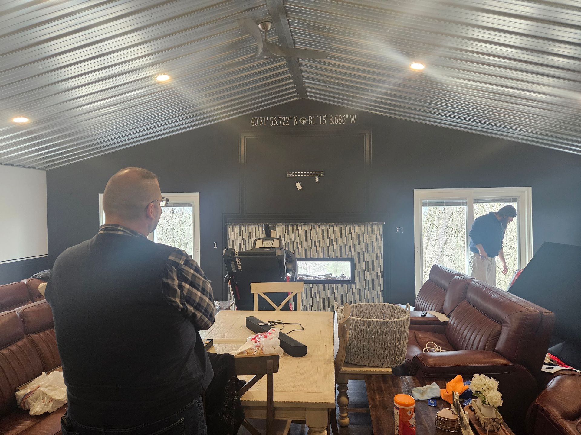 A man is standing in a living room looking at a fireplace.