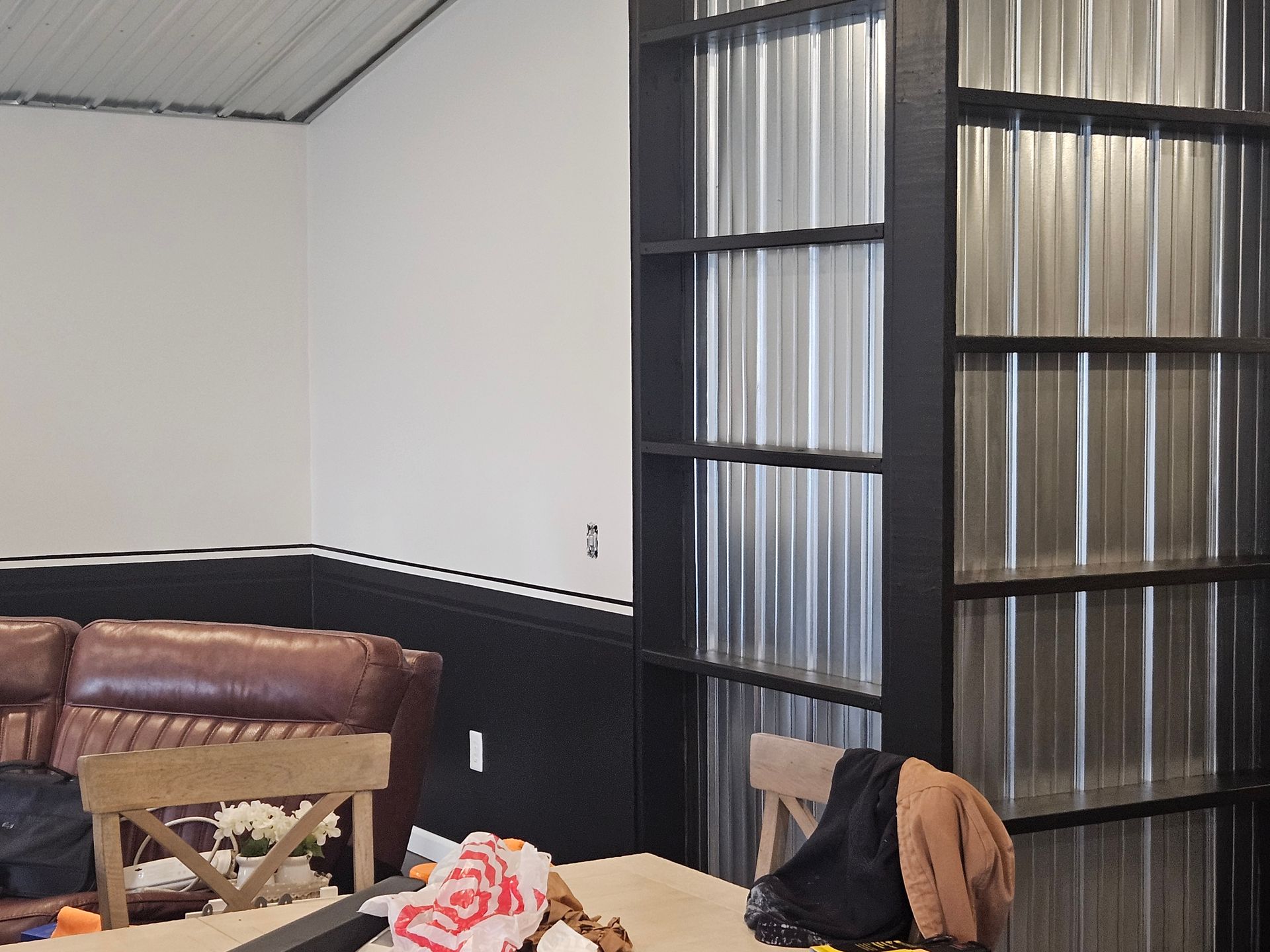 A living room with a table and chairs and a metal wall