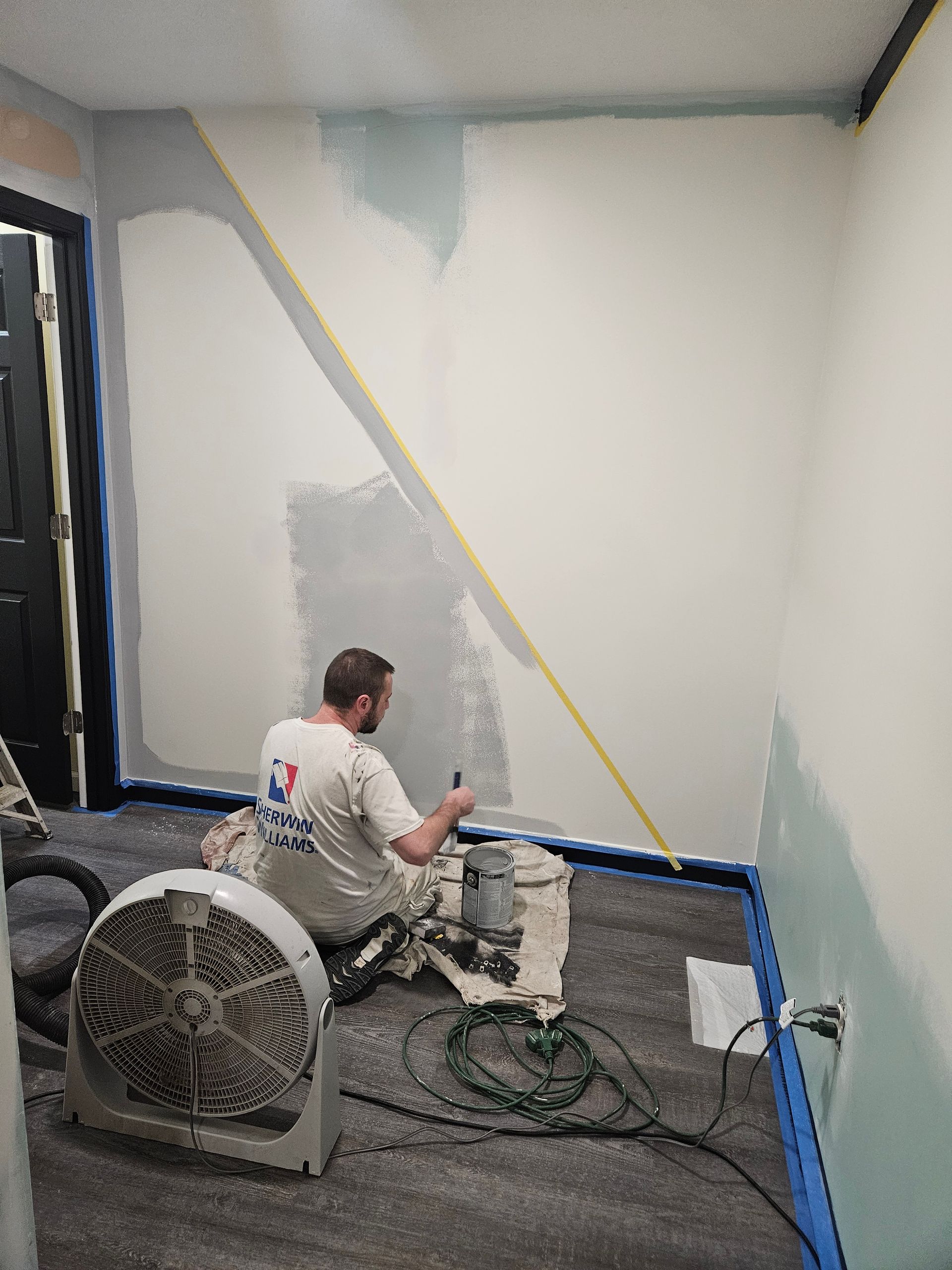A man is measuring a wall with a tape measure in a room.