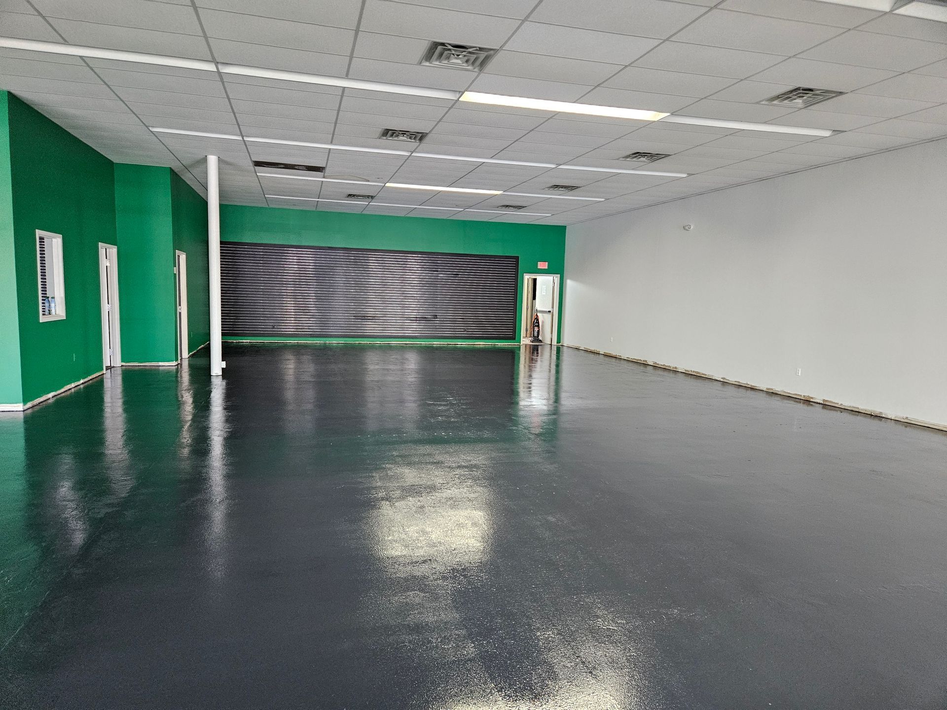 A large empty room with a black floor and green walls