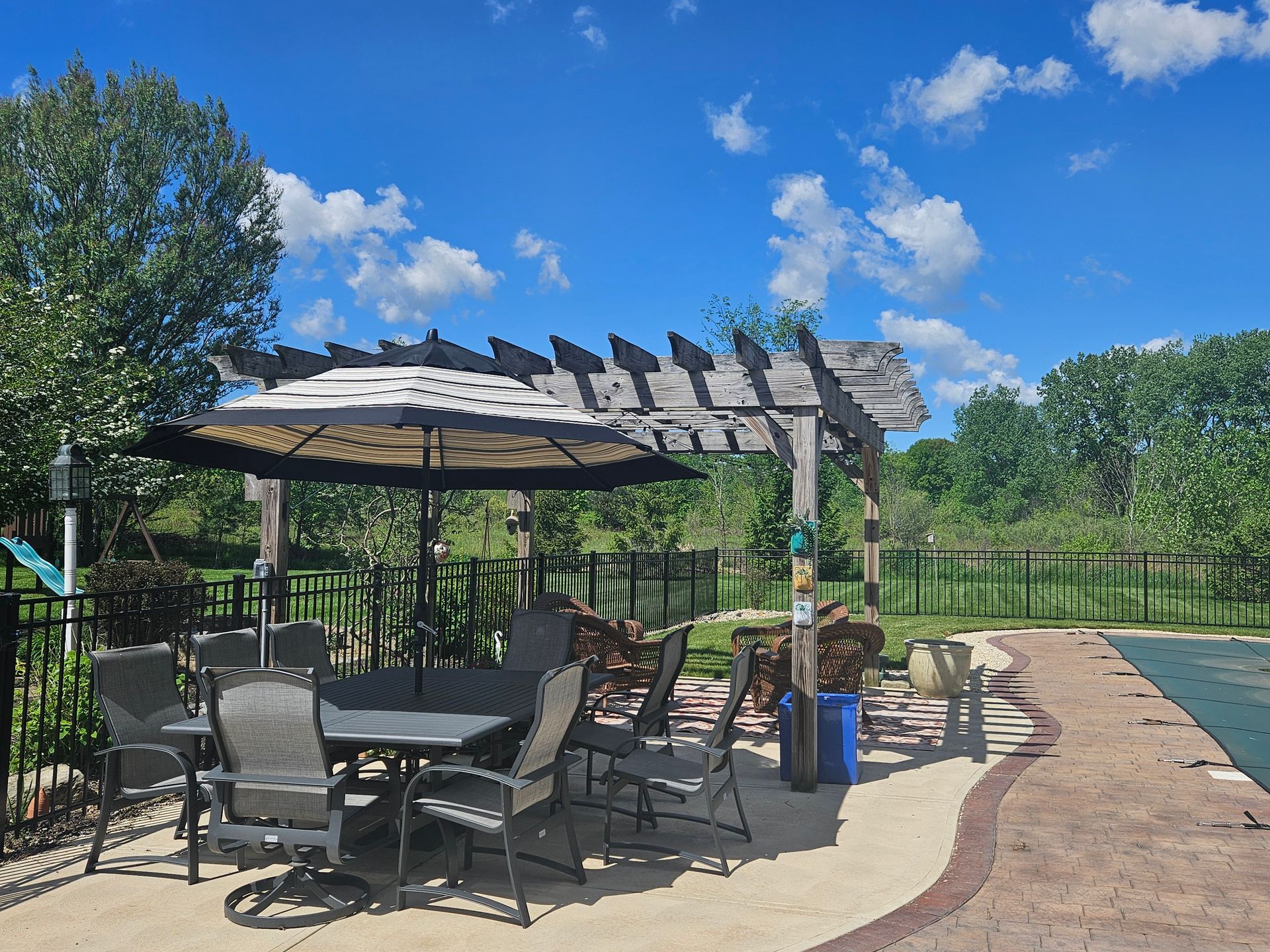 A table and chairs under a pergola next to a pool