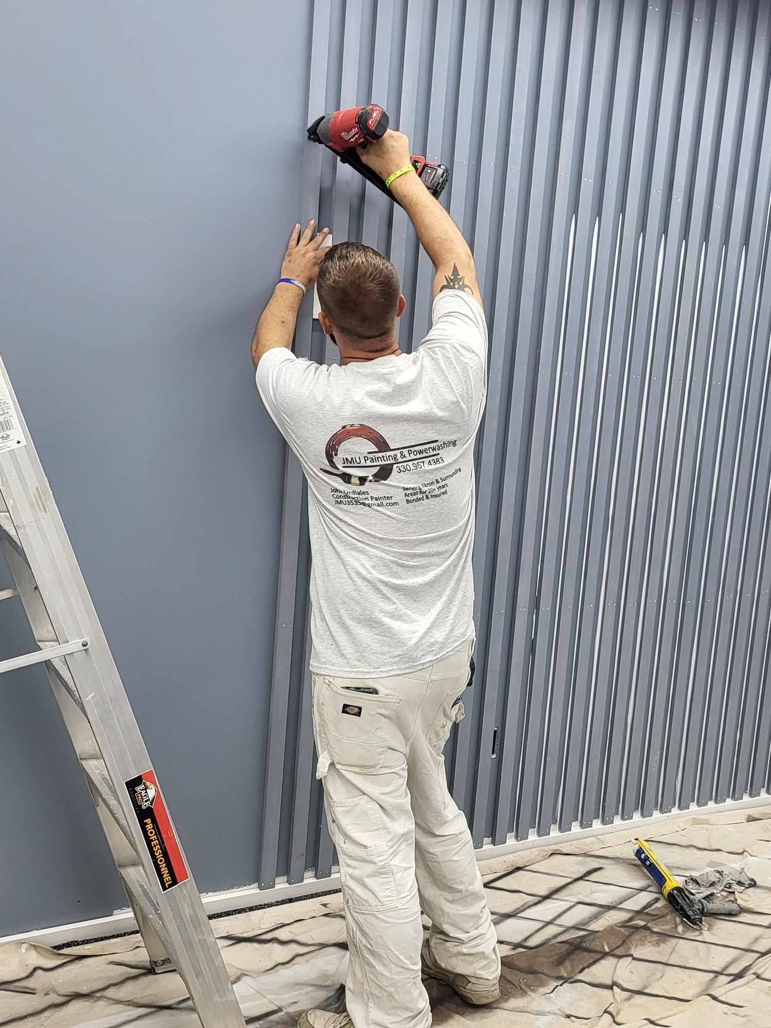 A man is installing vertical blinds on a wall.