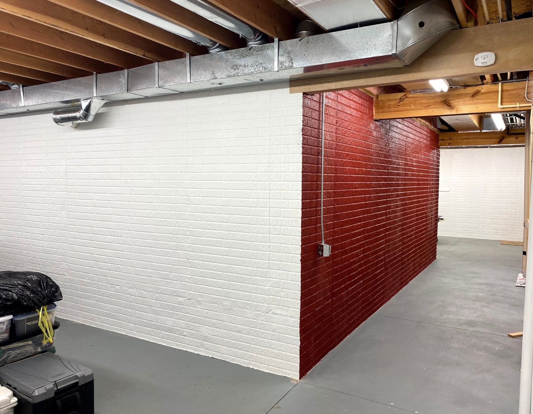 A basement with a red brick wall and white brick walls