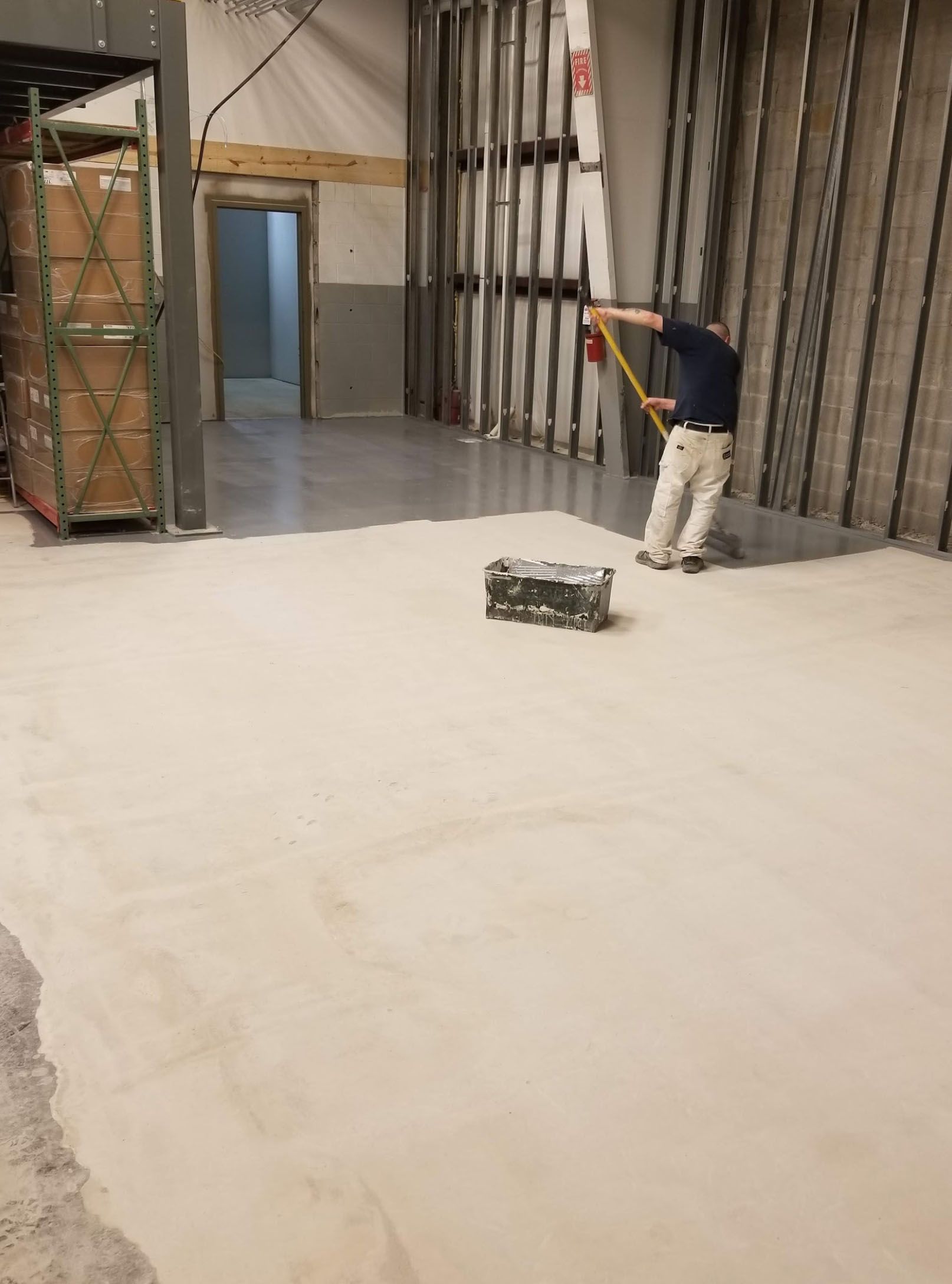 A man is measuring the floor of a building with a tape measure.