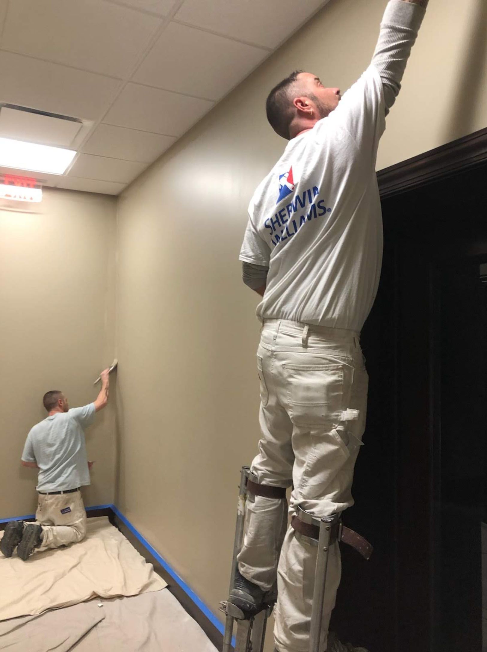 A man standing on a ladder painting a wall.