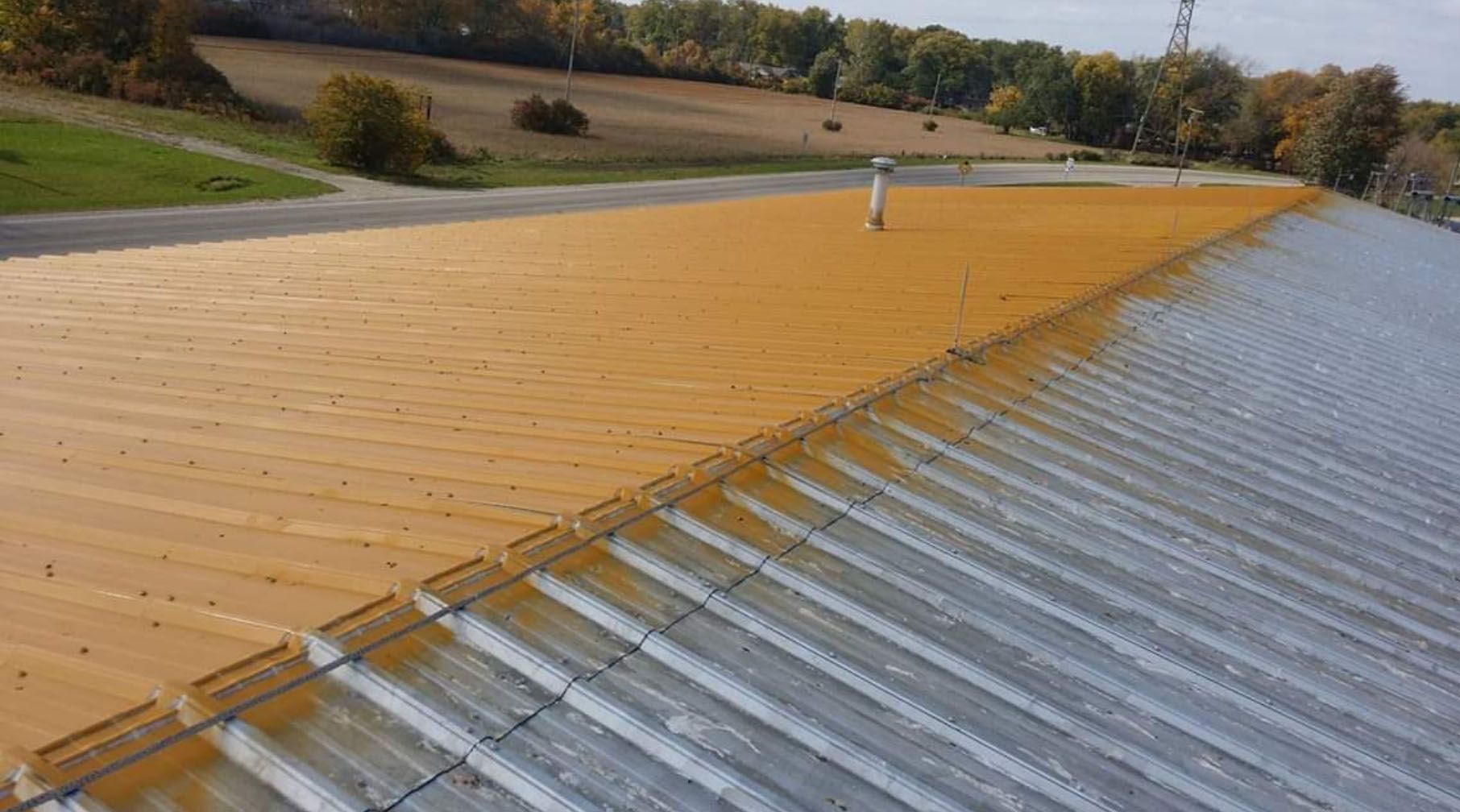 A roof with a lot of rust on it is being painted.