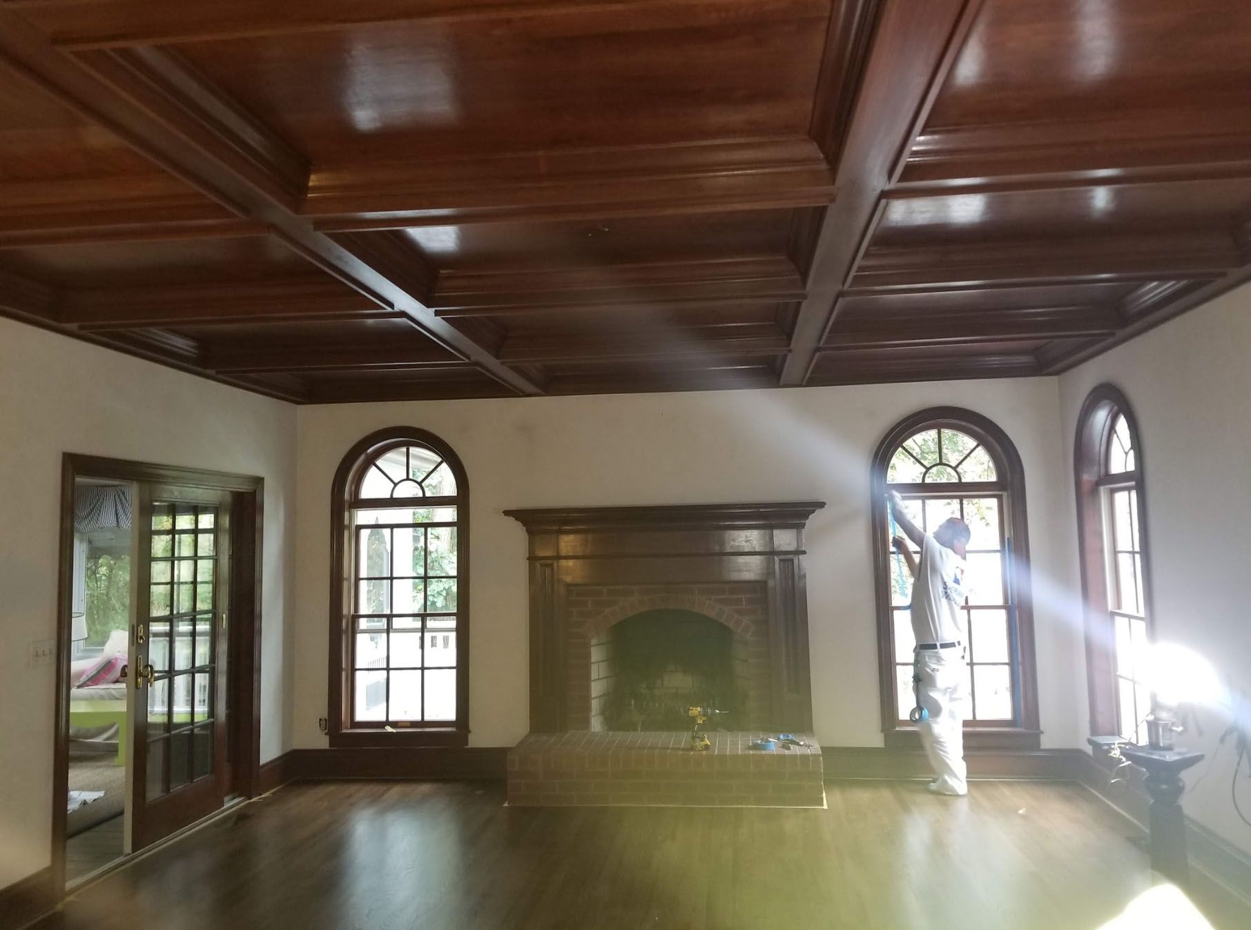 A man is standing in a living room with a fireplace and arched windows