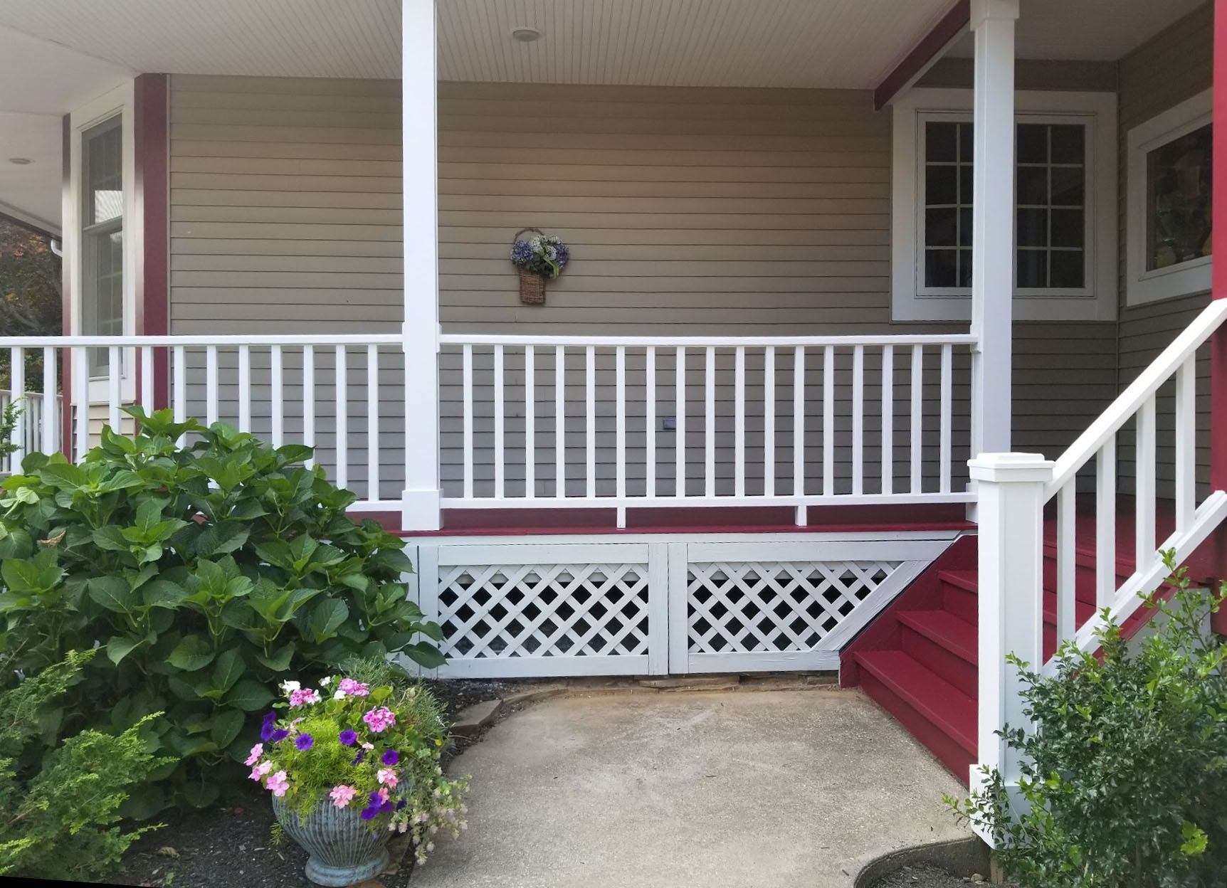 A porch with a white railing and red stairs