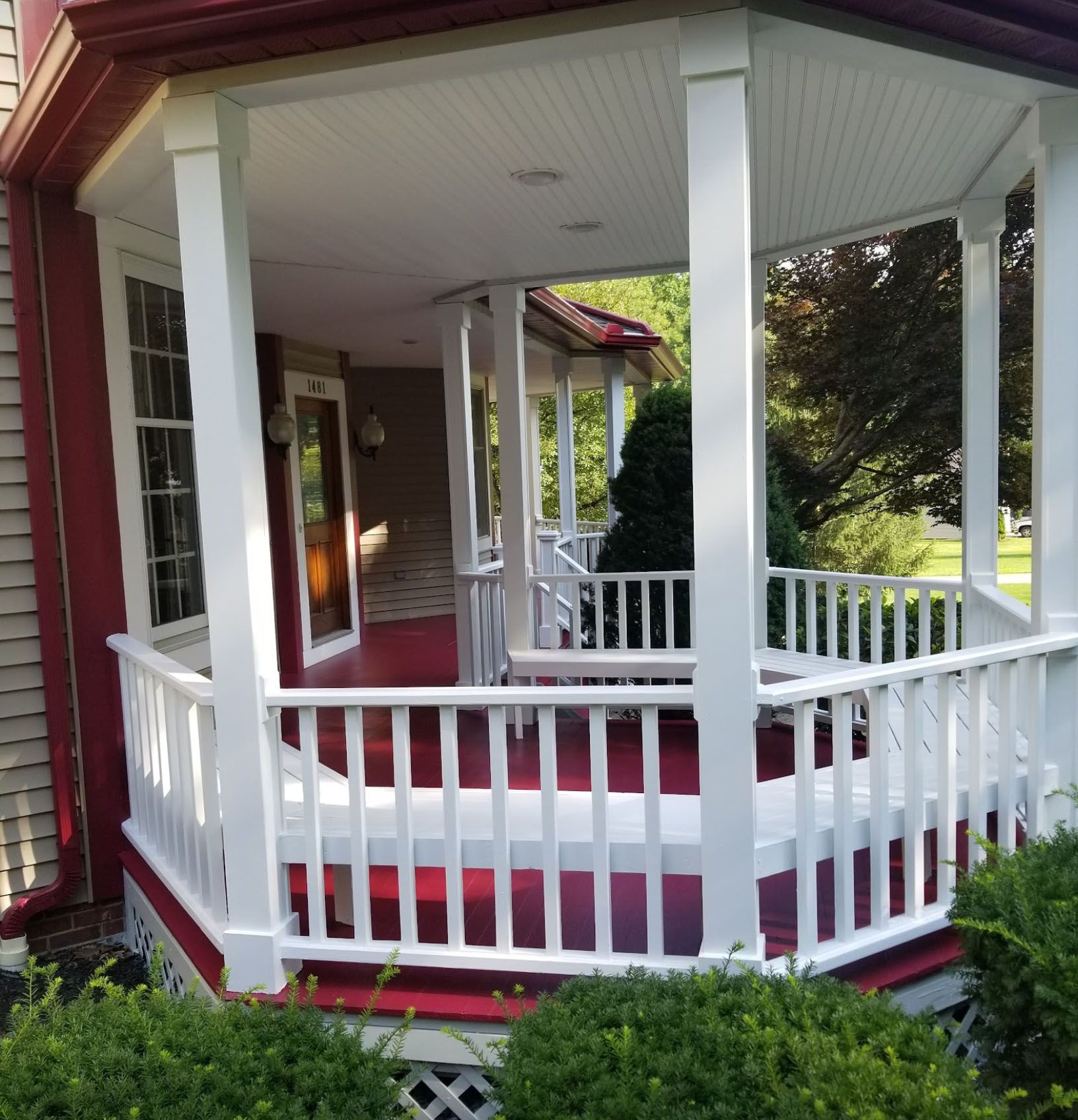 A porch with a white railing and a red rug