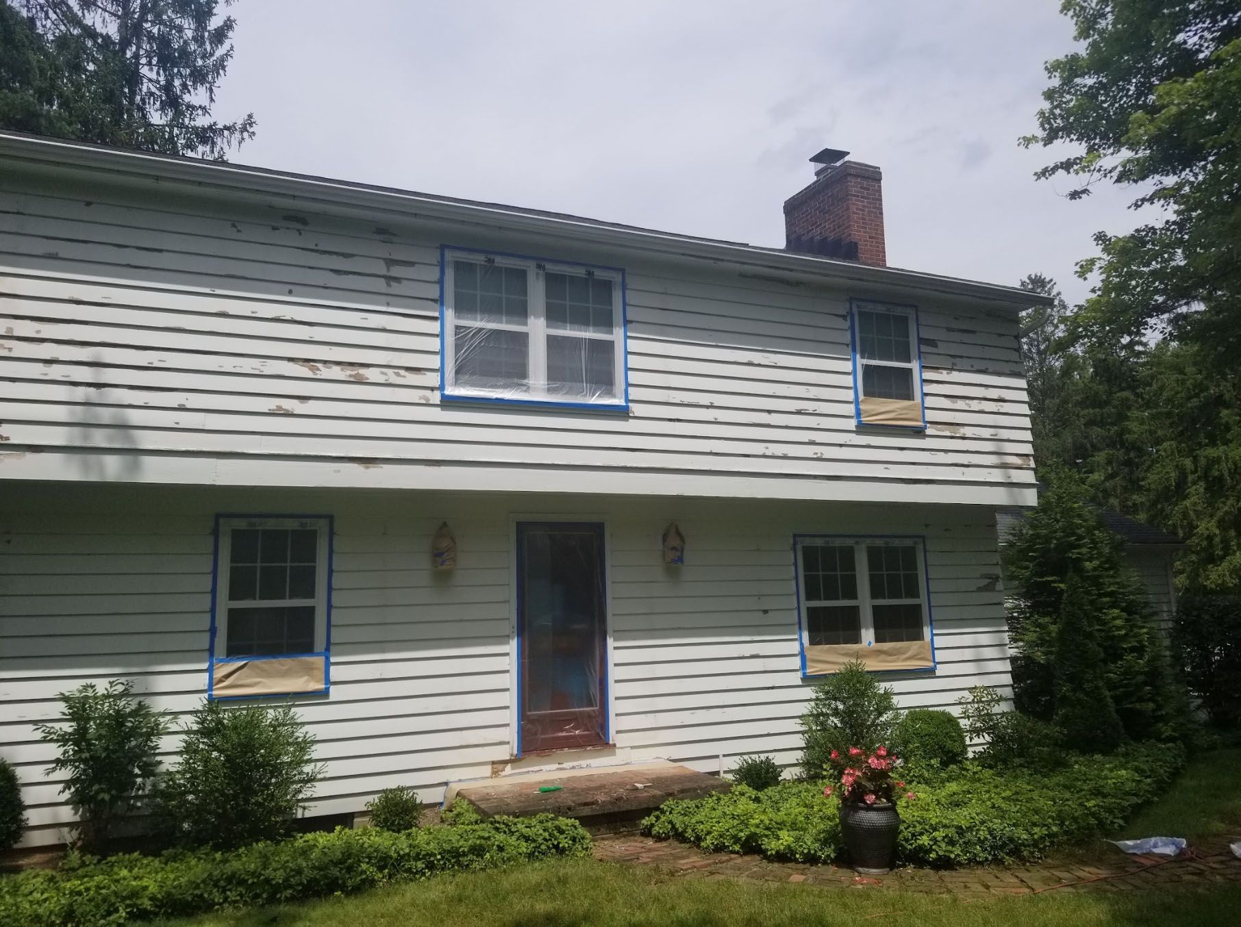 A white house with blue trim is being painted