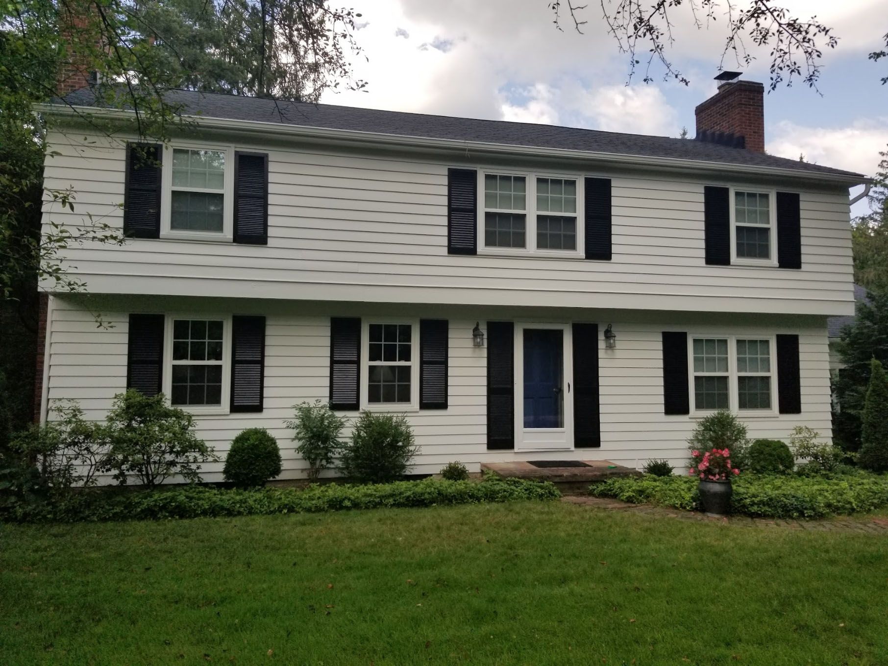 A white house with black shutters and a blue door