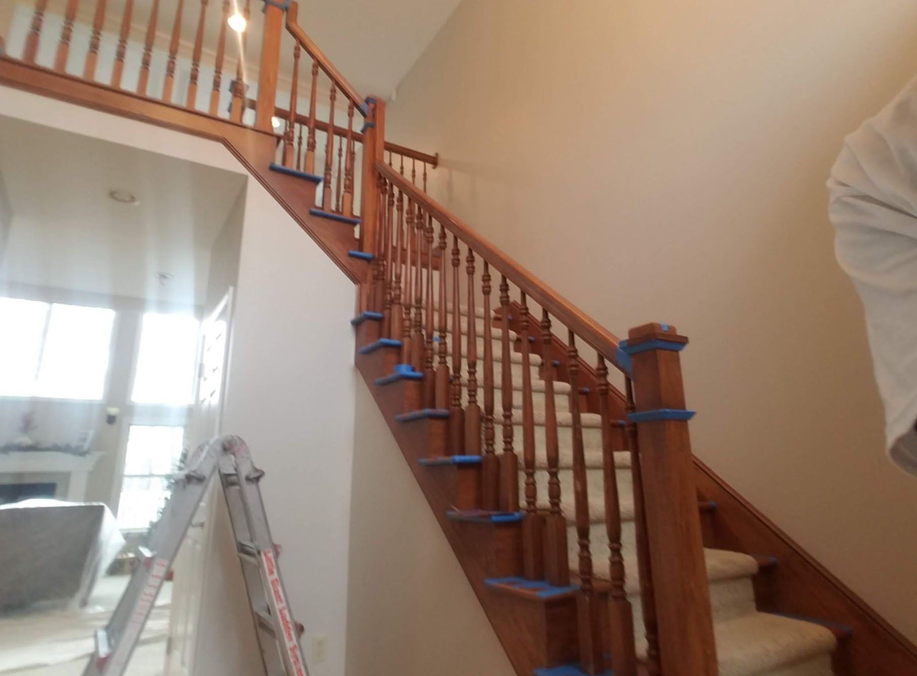 A wooden staircase with blue tape on the railing