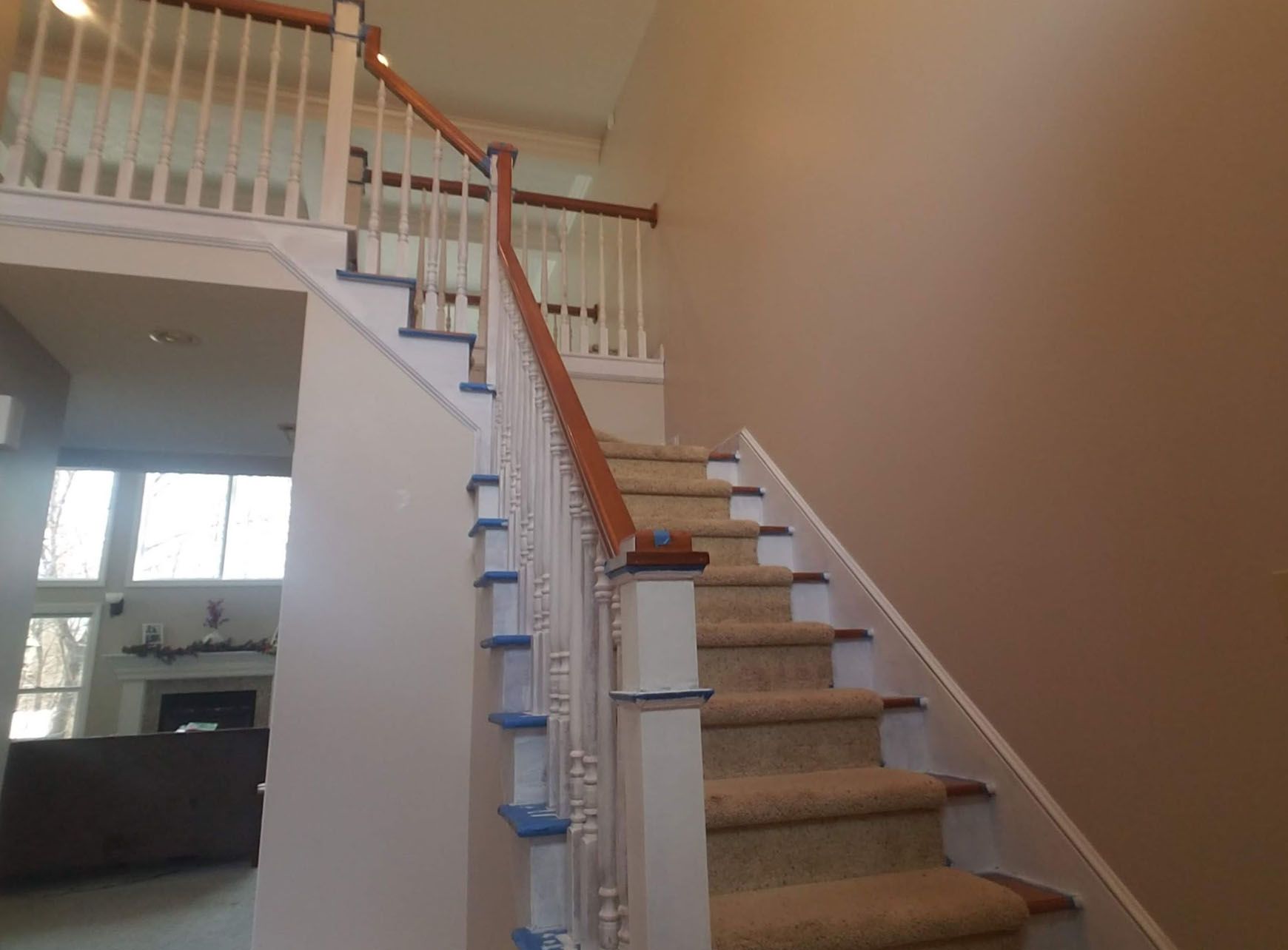 A staircase in a house with a carpeted staircase and a wooden railing.