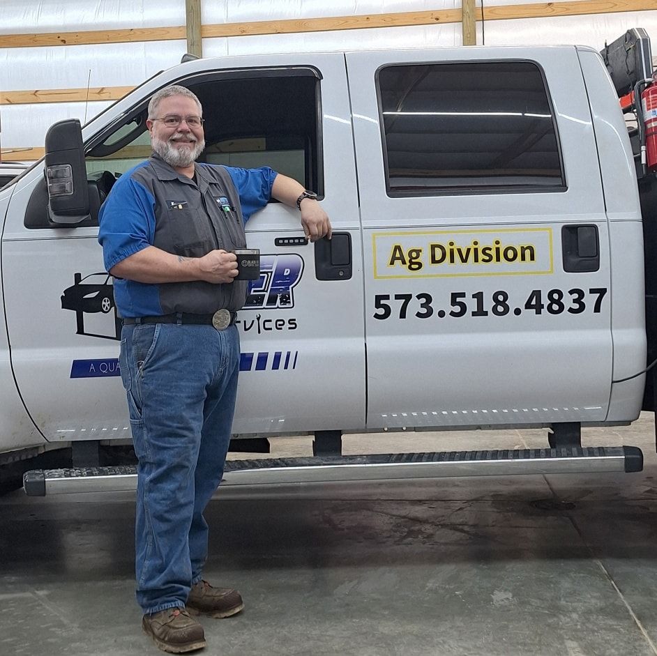 Man in work clothes leans on white truck with 