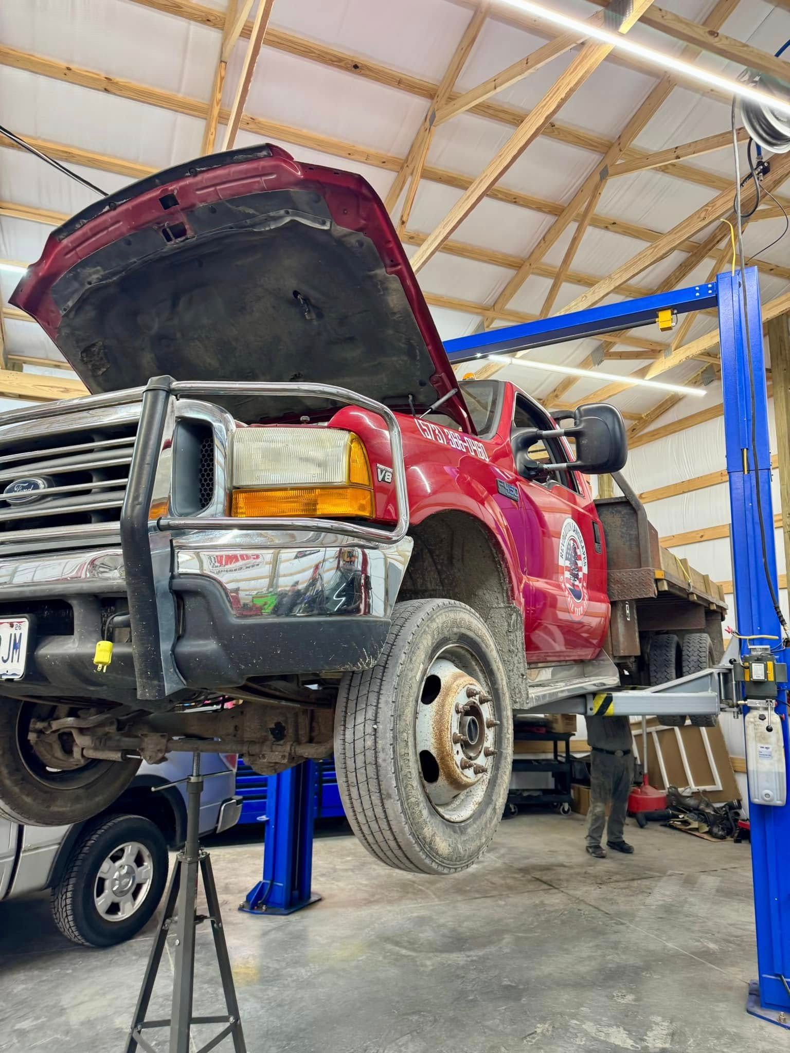 A red truck is sitting on a lift in a garage.