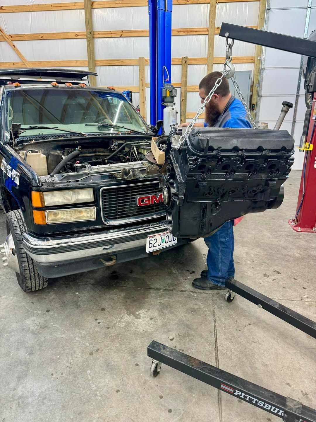 A man is working on a truck engine in a garage.
