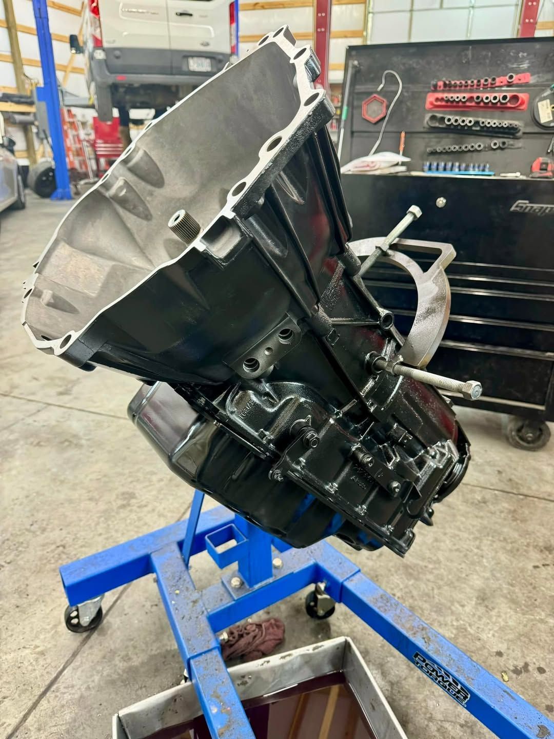 A car engine is sitting on a blue stand in a garage.