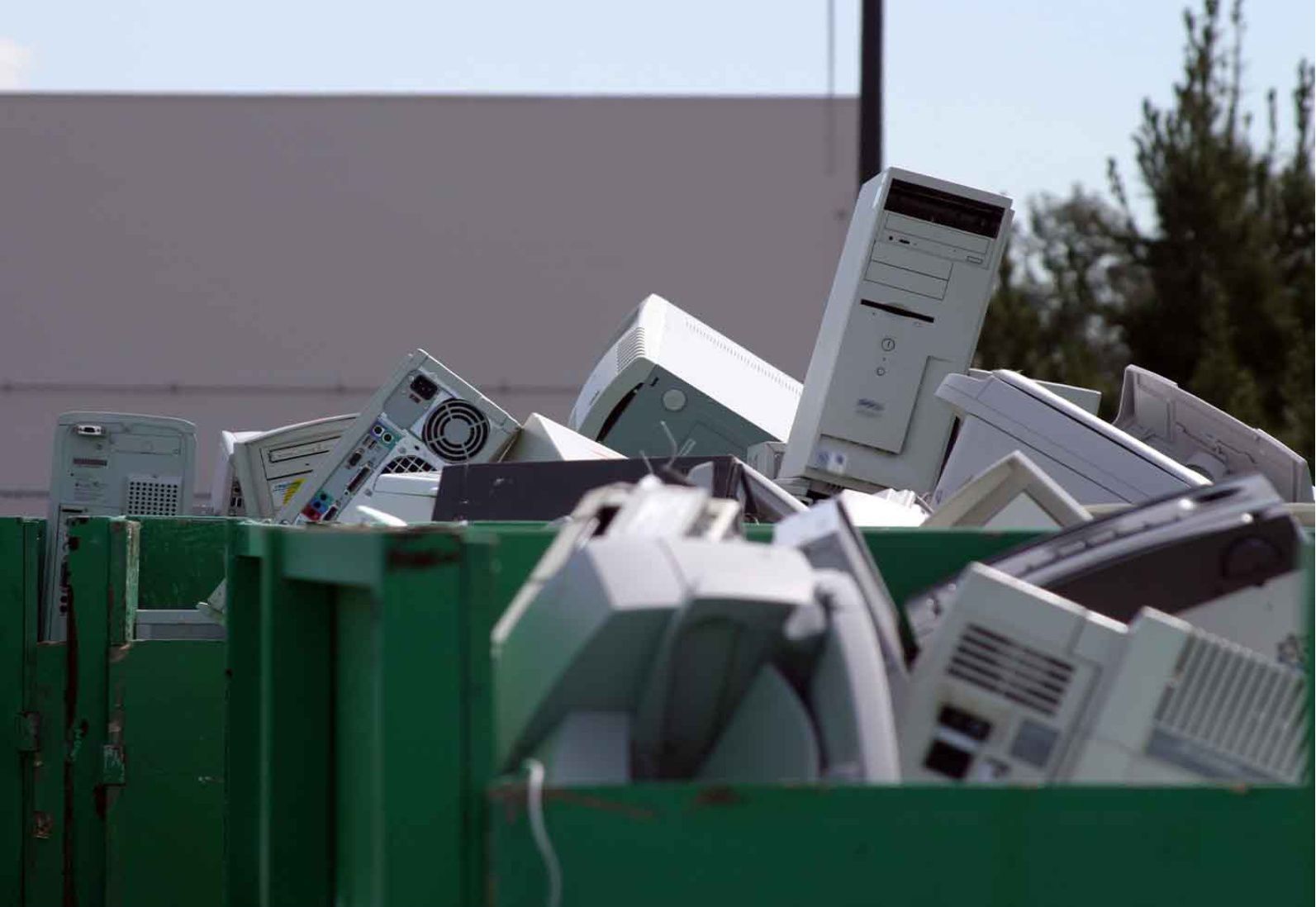 a green dumpster filled with lots of electronic waste