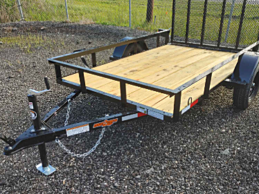 Black utility trailer with wooden bed, metal sides, and wire mesh gate.