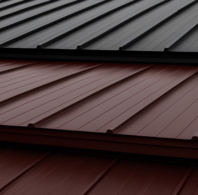 Stacked metal roofing panels in dark gray, maroon, and deep red, shown in close-up.