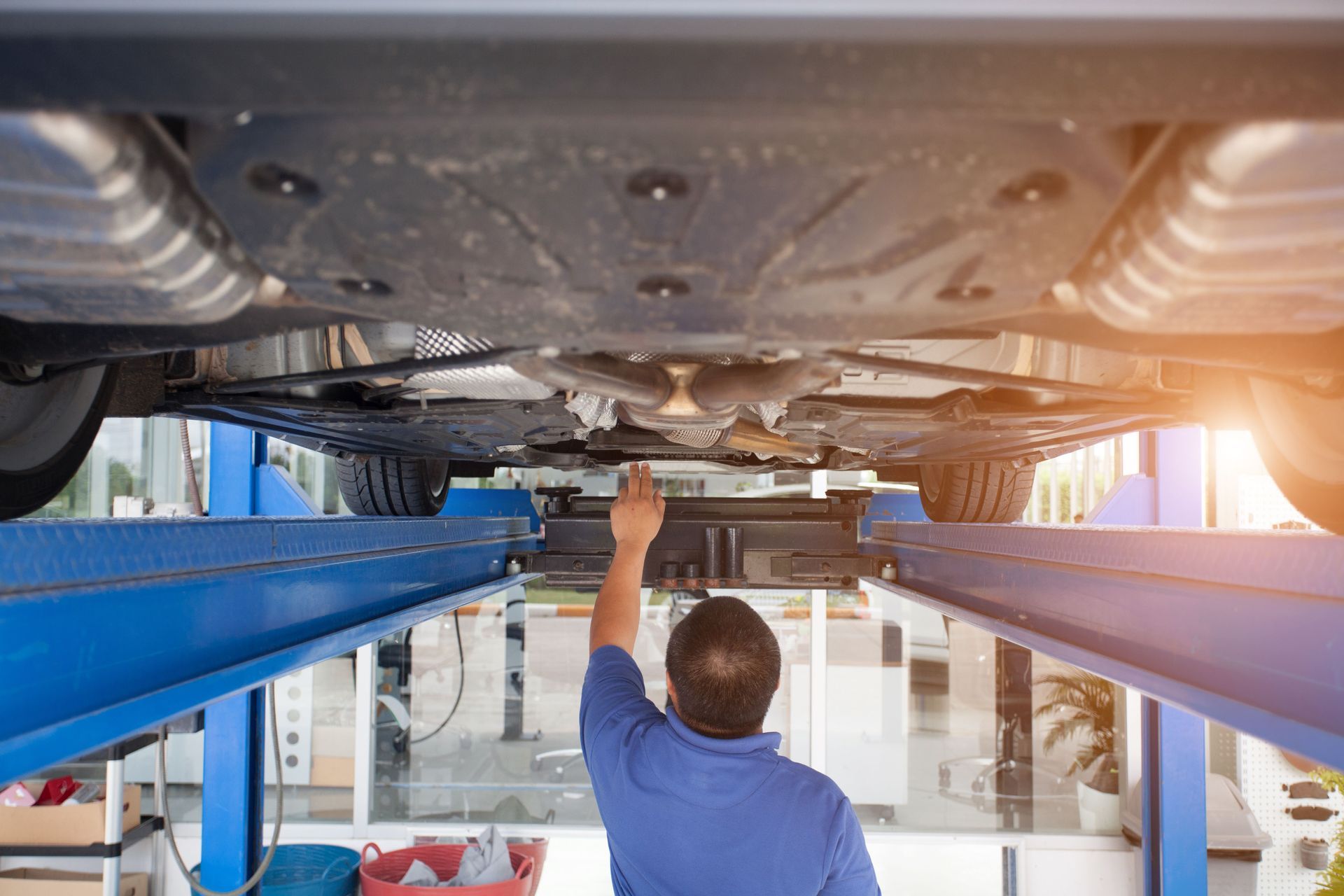 Low-angle view of a car’s chrome exhaust and rear diffuser on a lift in a garage