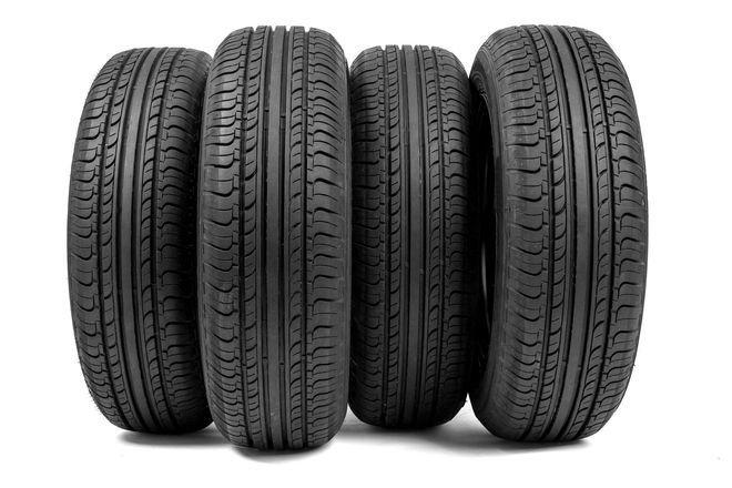 Four black car tires standing upright on a white background.