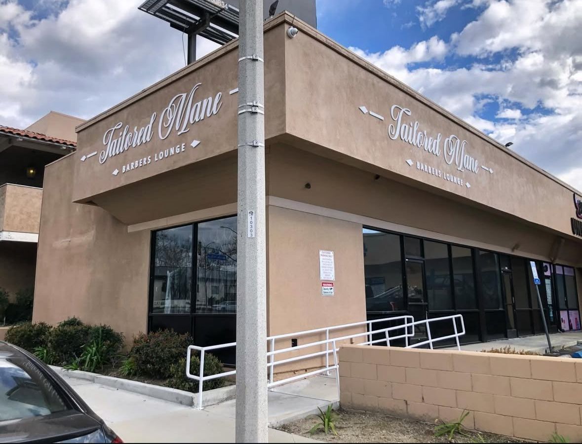 Exterior of "Toutant Blanc" bakery with accessible ramp. Tan stucco building, large windows, white sign.