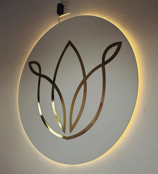 Gold floral logo on a white, backlit circular sign.