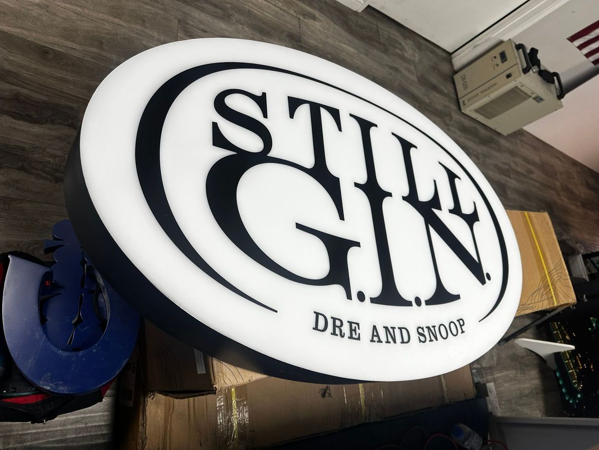 Round sign, white face, black lettering: STILL GIN. 
