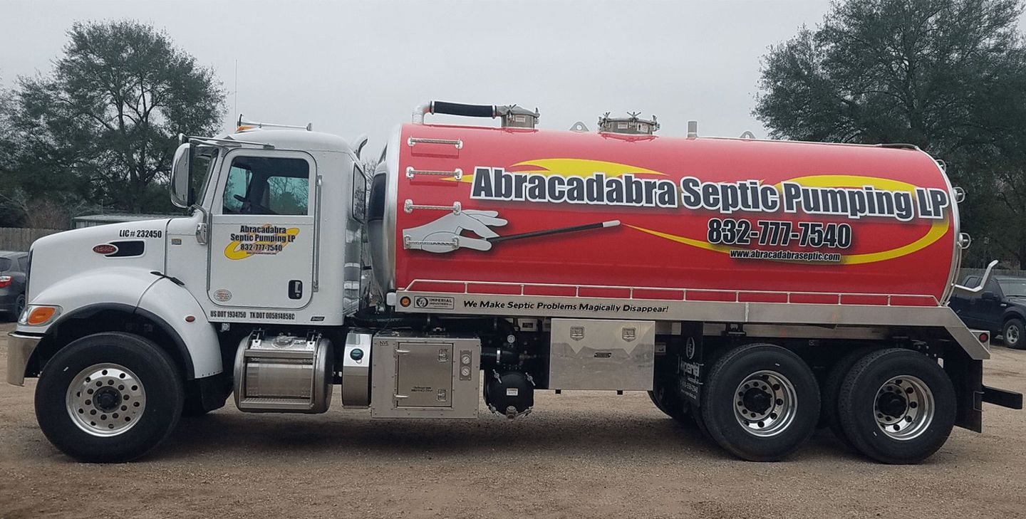 A red and white truck that says ' Abracadabra Septic Pumping ' on it