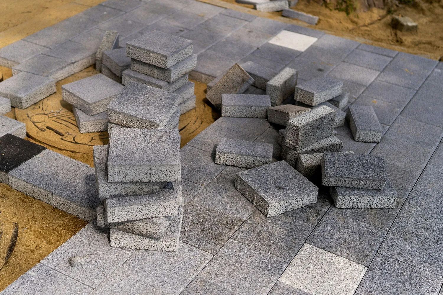 Gray paving stones stacked and laid out on sand for a patio.