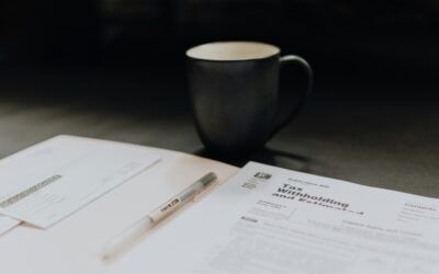 Black mug beside papers and a pen on a dark desk