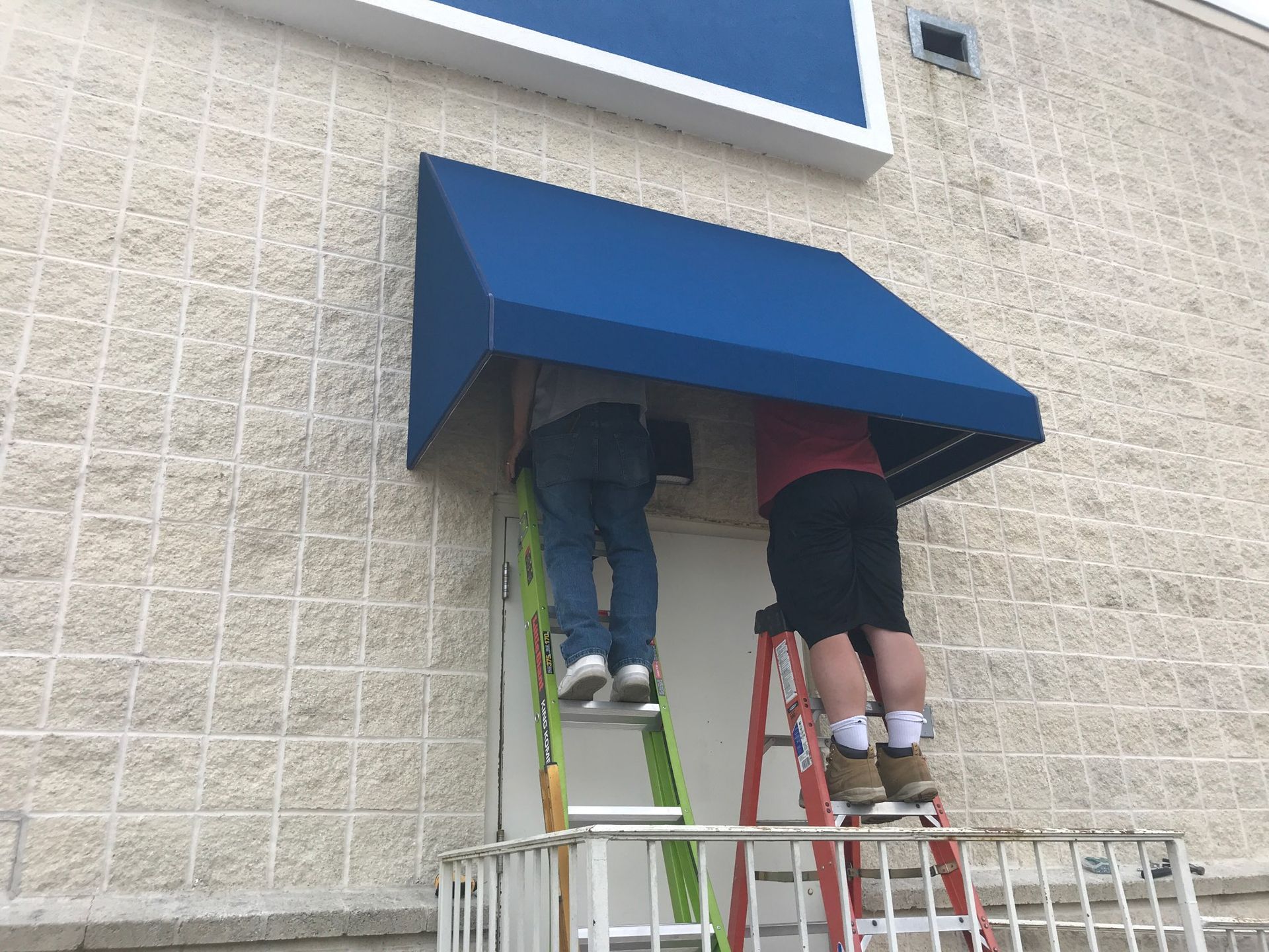 installing blue commercial door awning