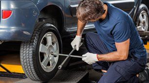 Male mechanic fixing car tire with rim wrench at garage