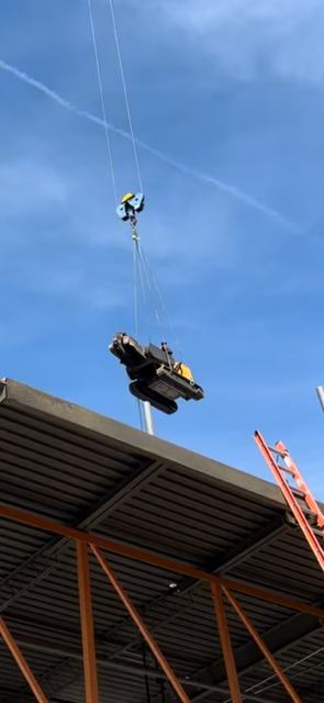 A crane is lifting a car from the roof of a building.
