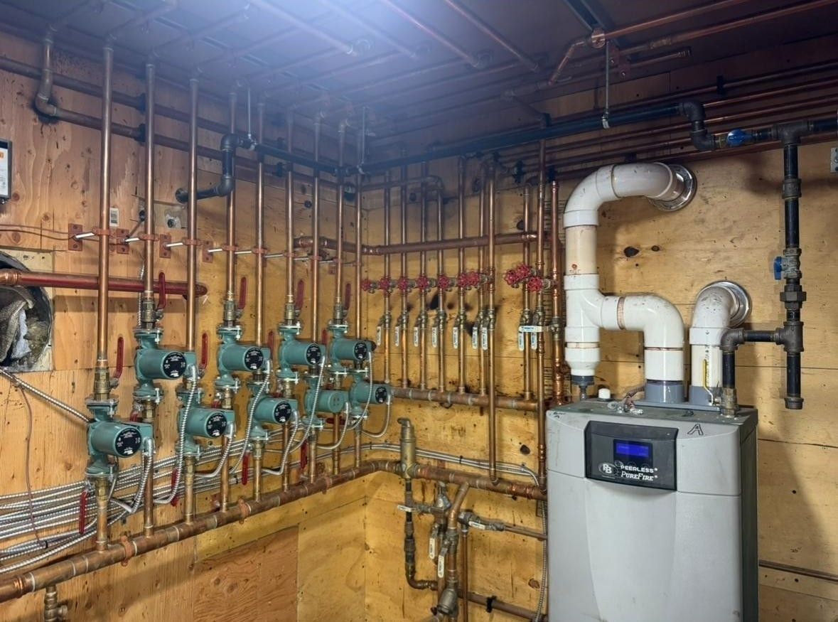 Boiler room with pipes, valves, and a water heater against unfinished wooden walls