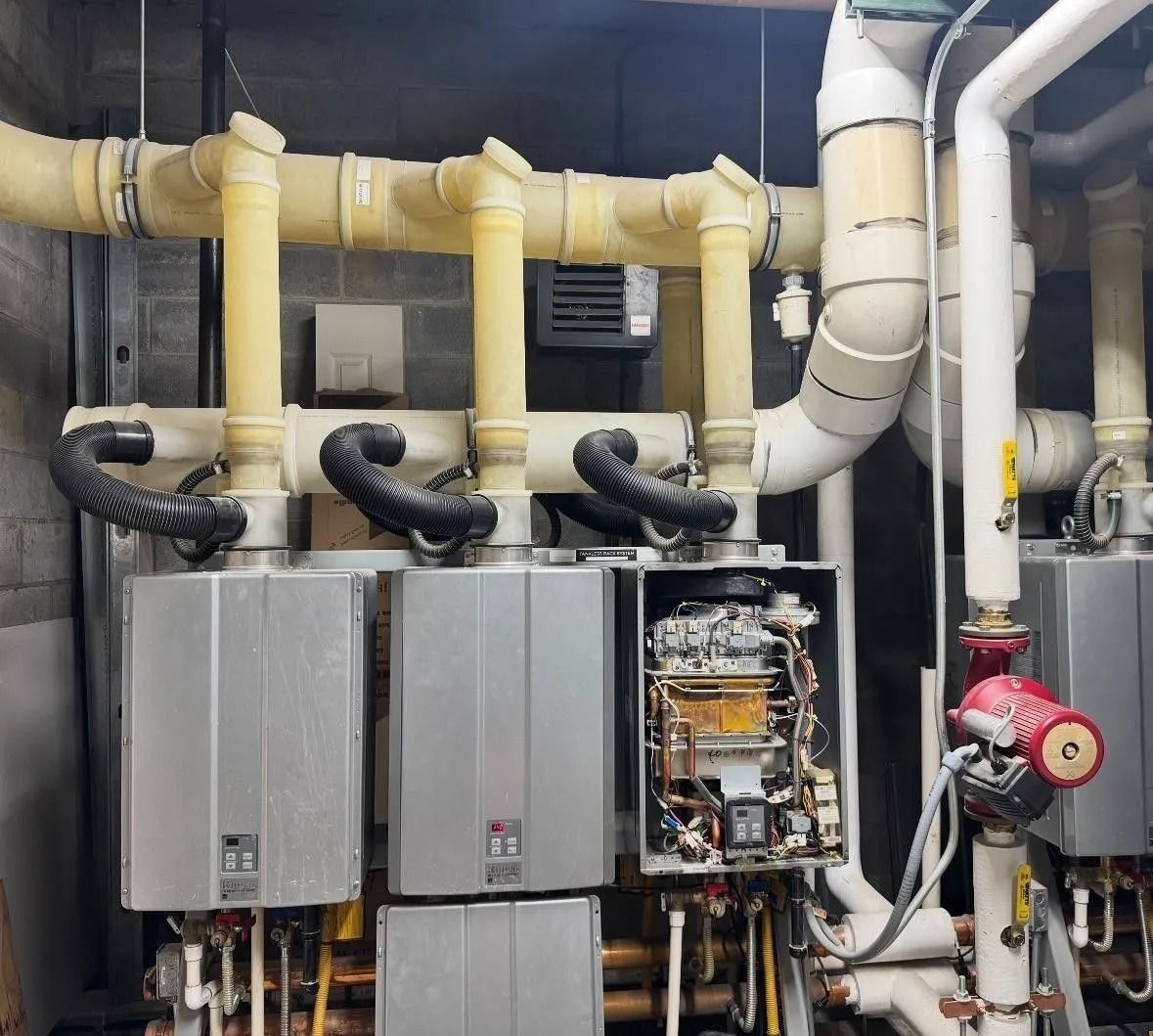 Industrial HVAC machinery with pipes, control boxes, and exposed wiring in a mechanical room