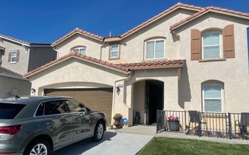 A car is parked in front of a large house with exceptional exterior painting