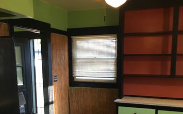 A kitchen with green walls and red shelves and a window