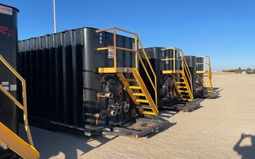 A row of black tanks with yellow stairs on top of them.